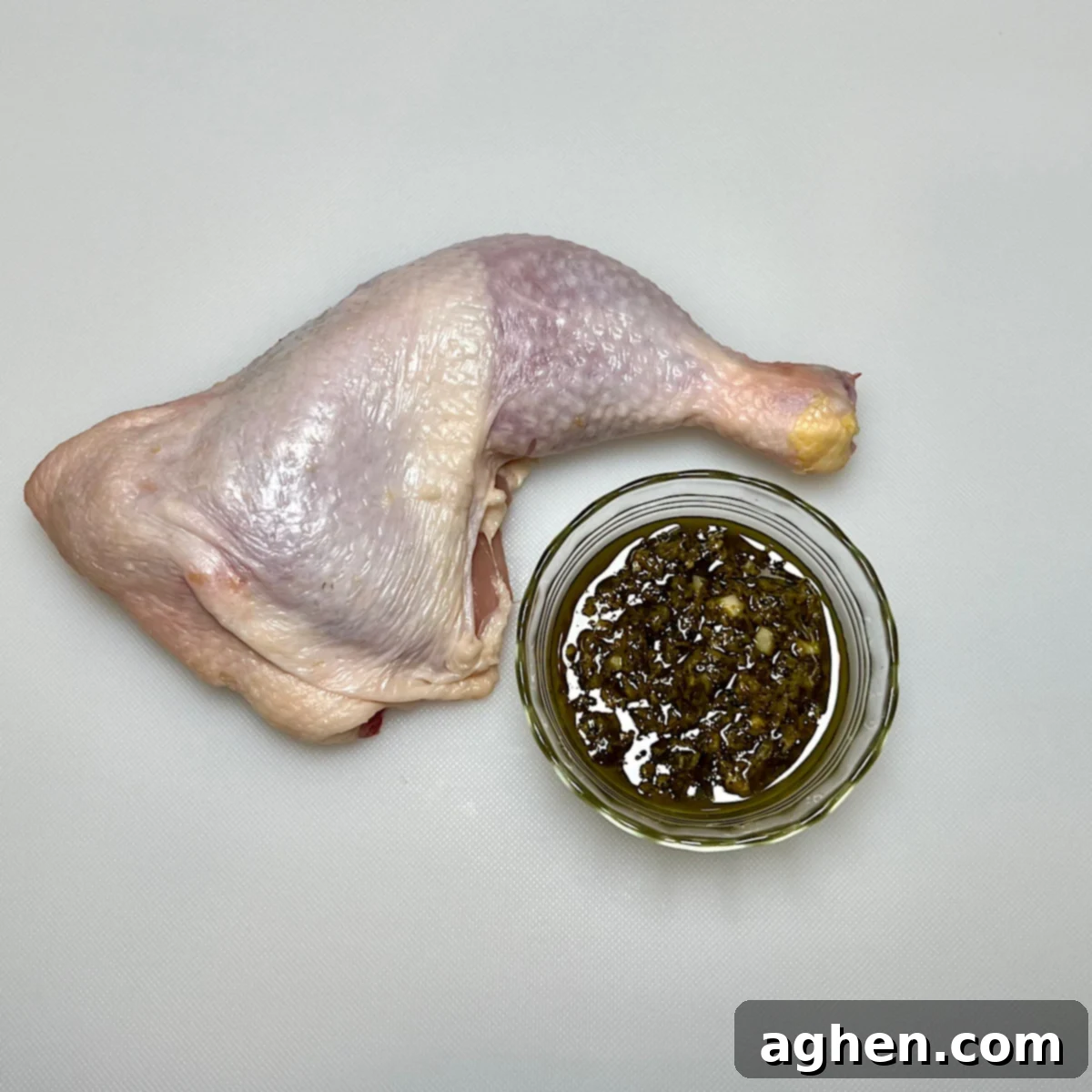 Chicken leg quarter with pesto being applied under the skin.