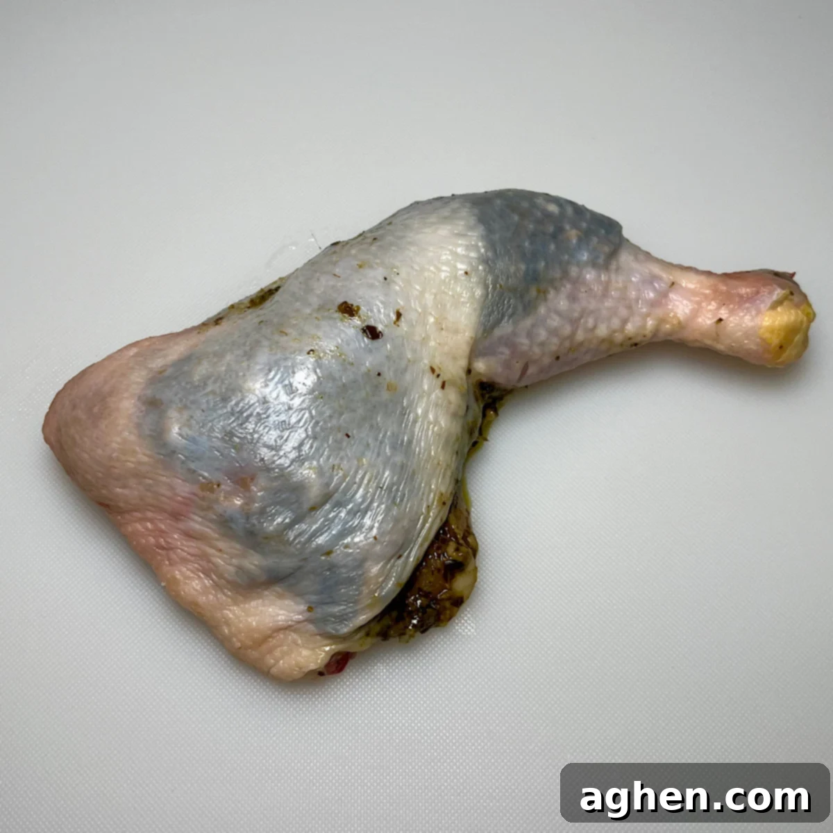 Close-up of a chicken leg quarter with pesto neatly tucked under the skin.
