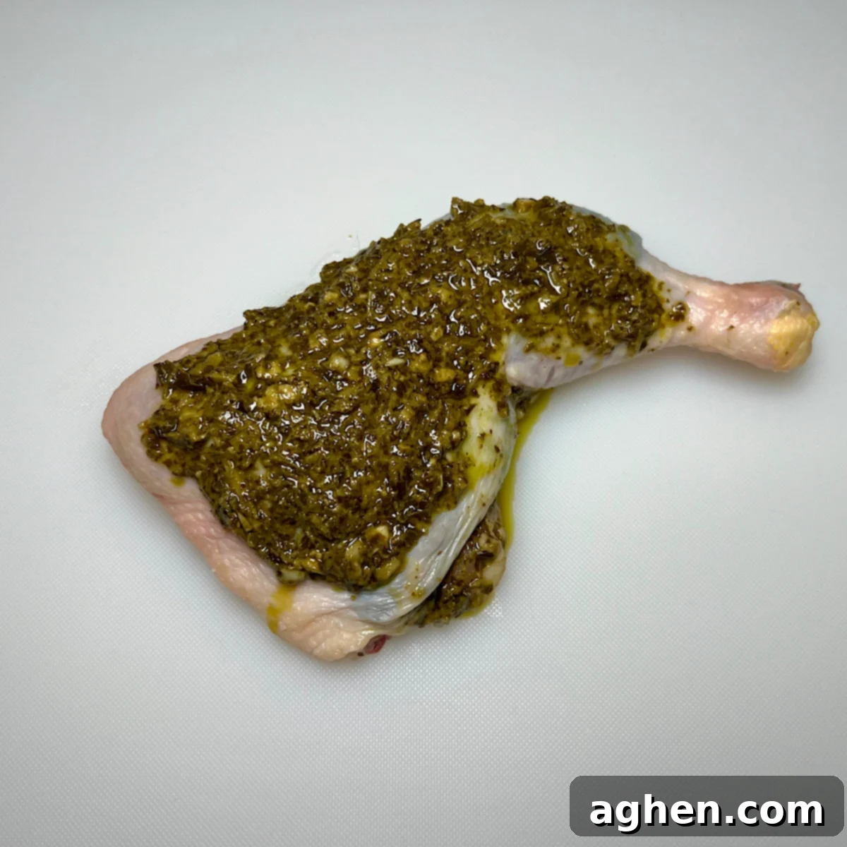 Chicken leg quarter completely covered with pesto on top.