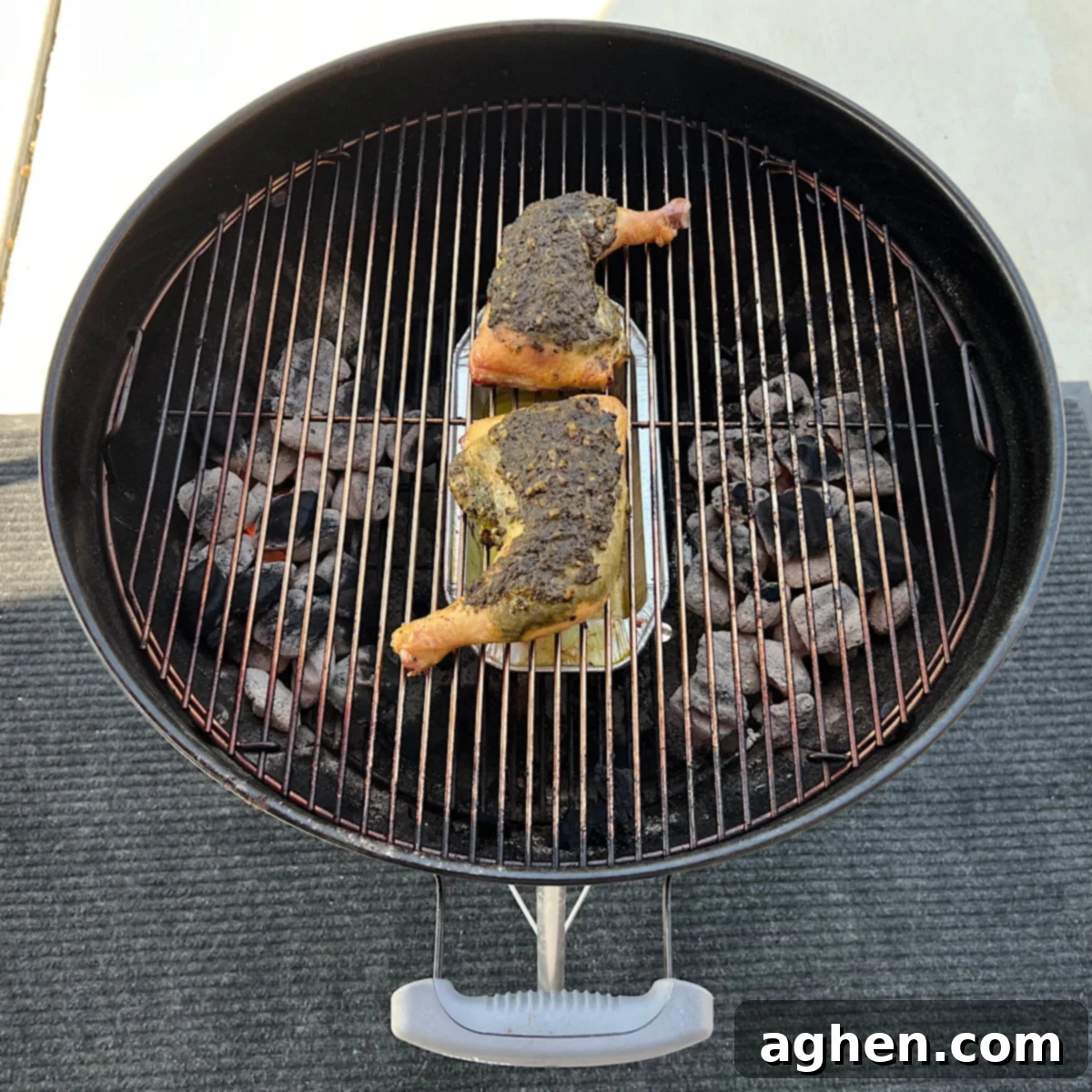 Pesto chicken leg quarters grilling on a Weber Kettle.