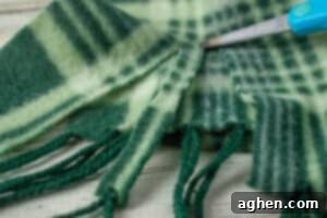 Green plaid scarf being cut into strips with scissors