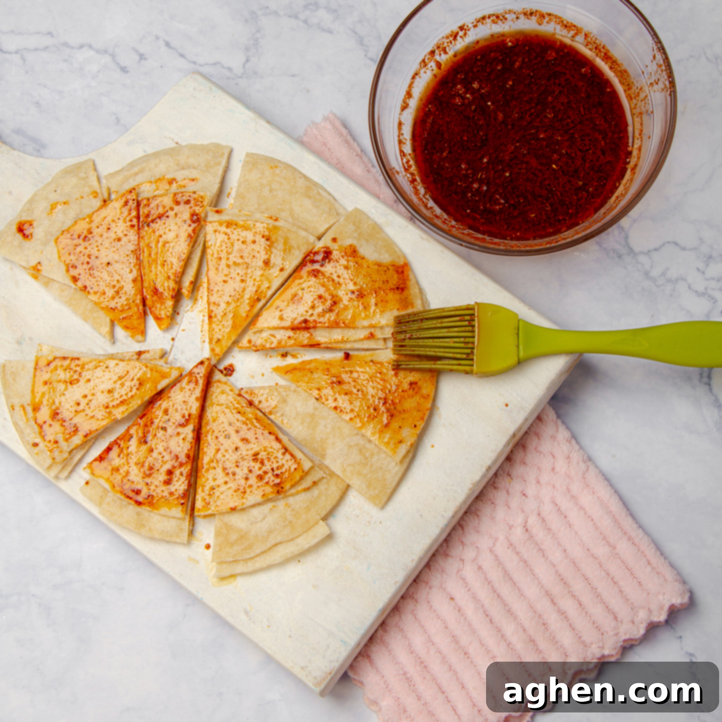 Weight Watchers Diyeti İçin Harika Ev Yapımı Tostitos Atıştırmalığı 6 Tortilla triangles, lightly brushed with the seasoning mixture, arranged on a cutting board.