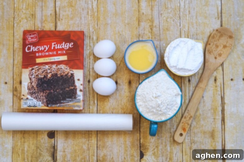 Ingredients for Brownie Mix Cookies: box of brownie mix, 3 eggs, melted butter, all-purpose flour, and powdered sugar, shown with parchment paper and a wooden spoon on a rustic surface.