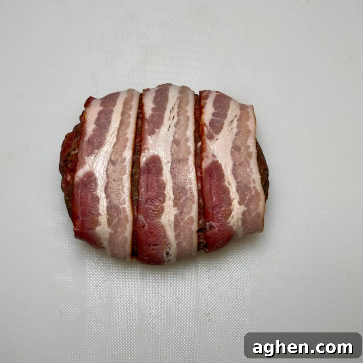 bacon wrapped burger patty, showing the wrapping technique