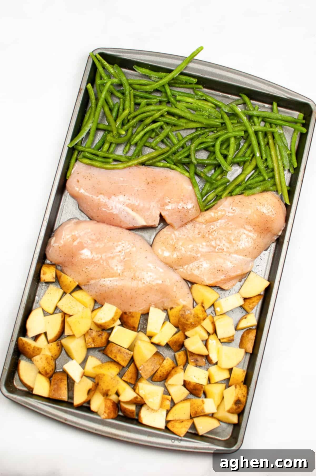 Green beans, three chicken breasts, and diced potatoes on sheet pan