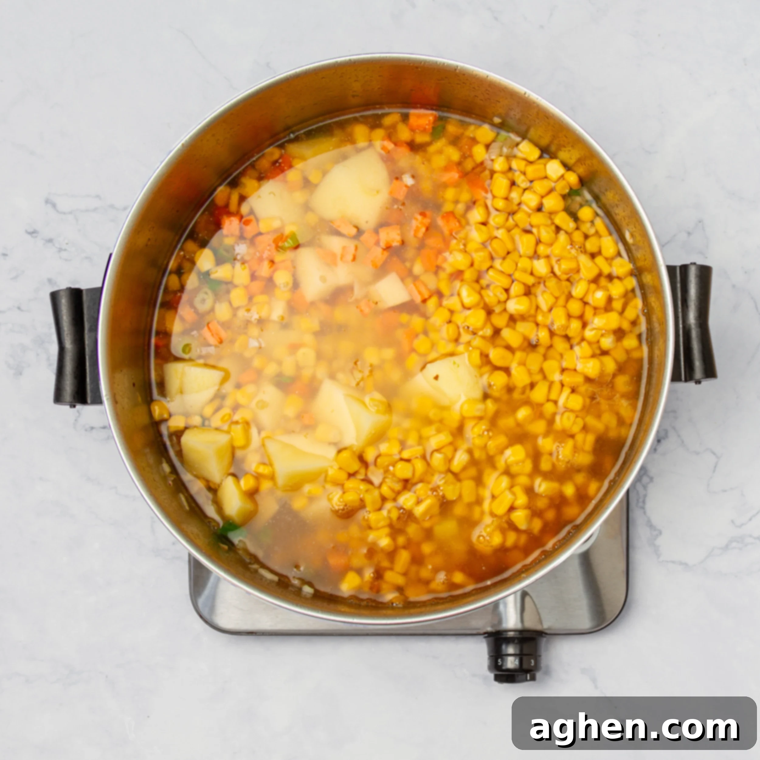 Sauteed veggies simmering in broth in a pot. 