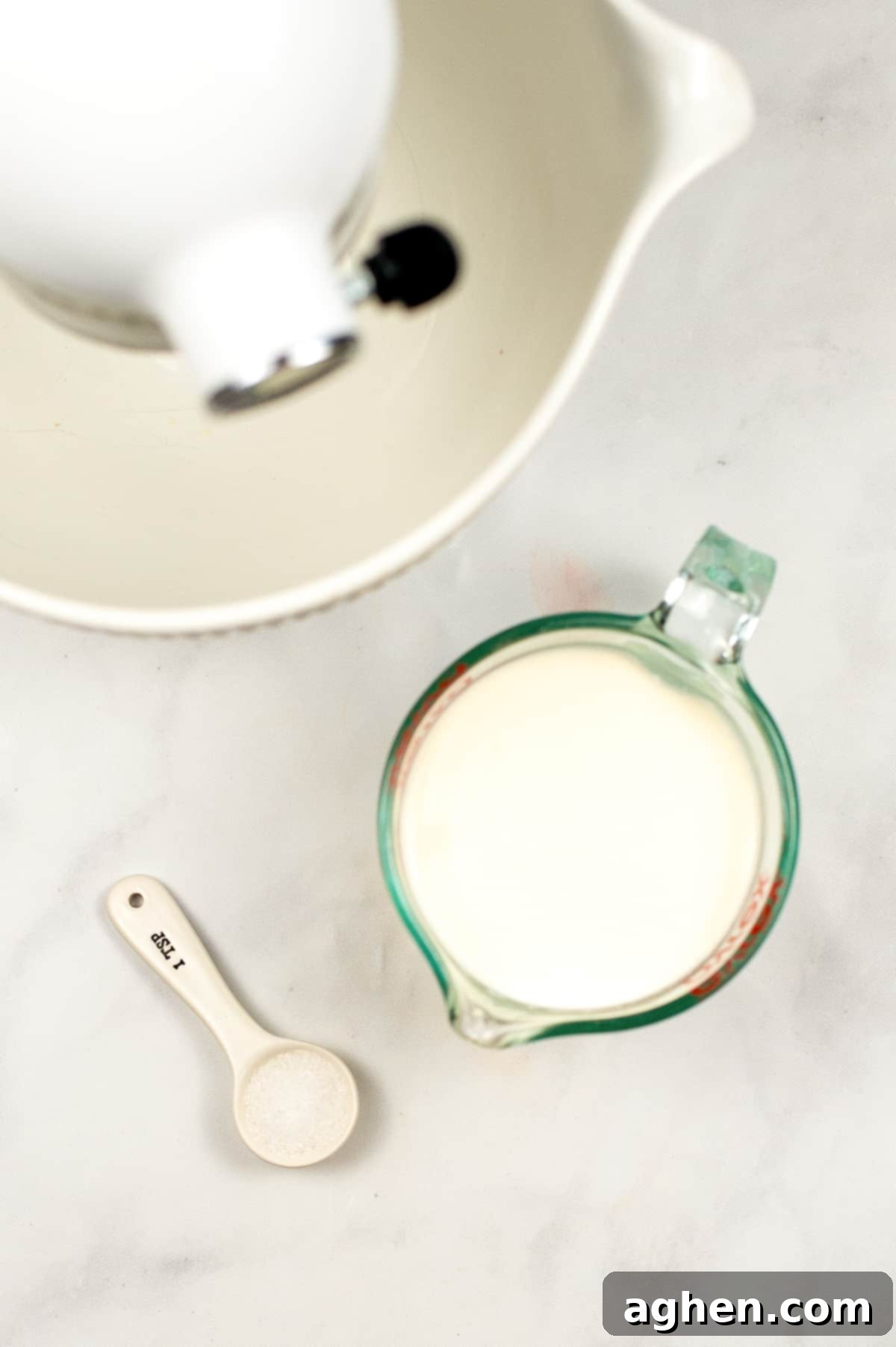 From Cream to Gold 4 Stand mixer, measuring cup filled with cream, and teaspoon of salt, showing ingredients for homemade butter.