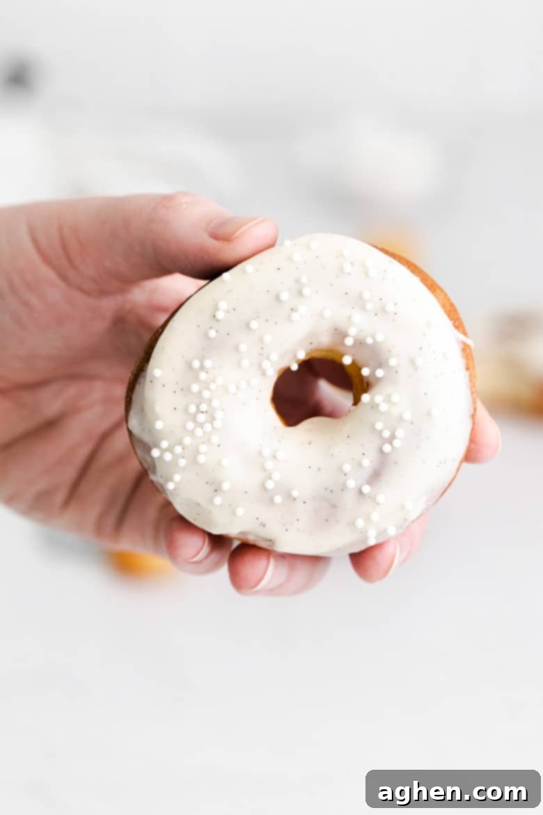 hand holing doughnut with vanilla frosting