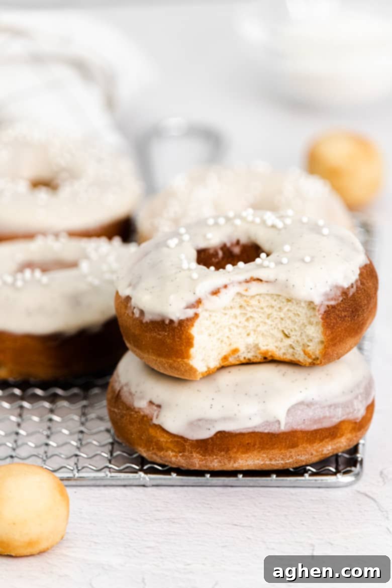 several homemade air fryer donuts with vanilla icing, one with bite taken out of it to show cake-like inside