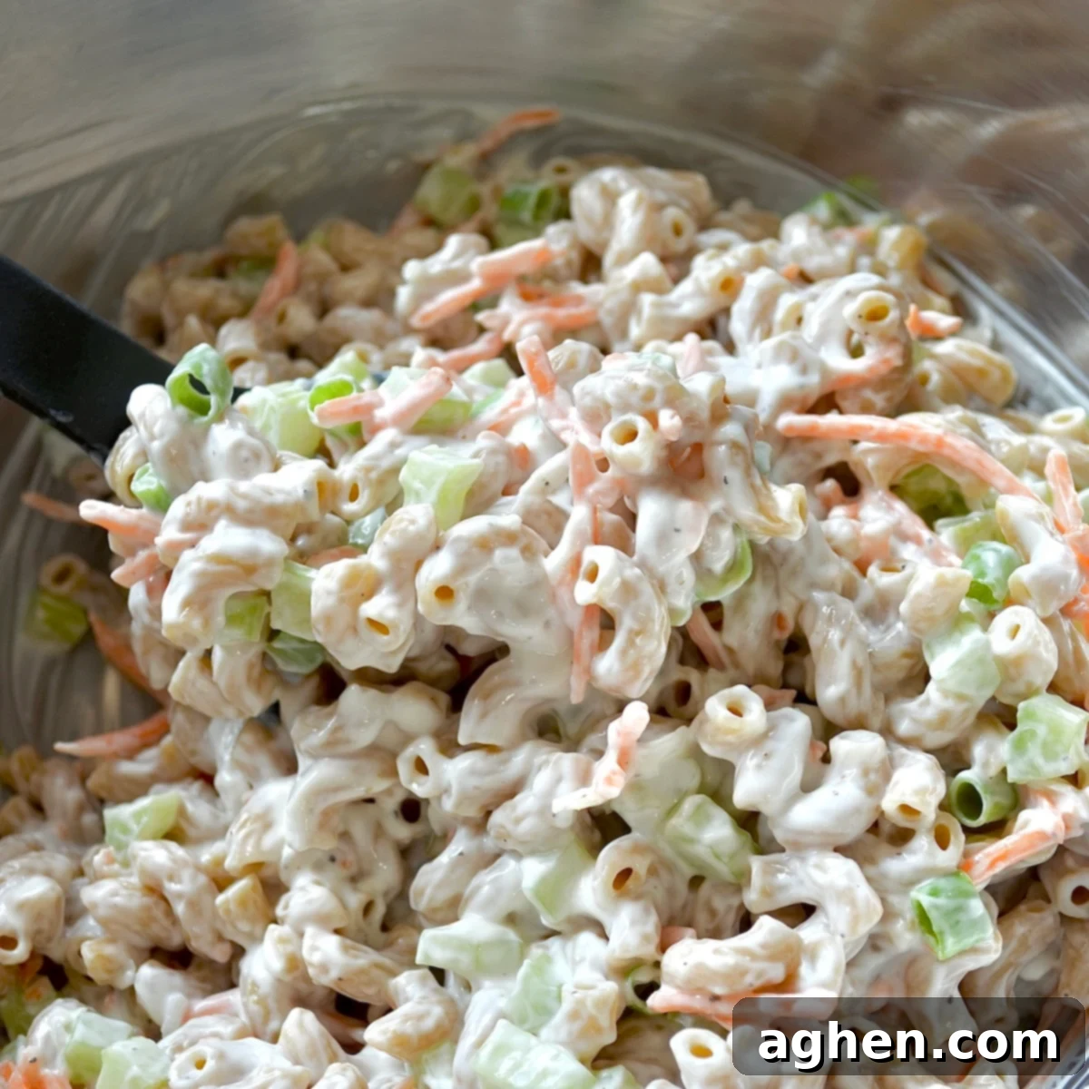 A large bowl of Hawaiian macaroni salad with creamy dressing, garnished with fresh herbs, ready to be chilled.
