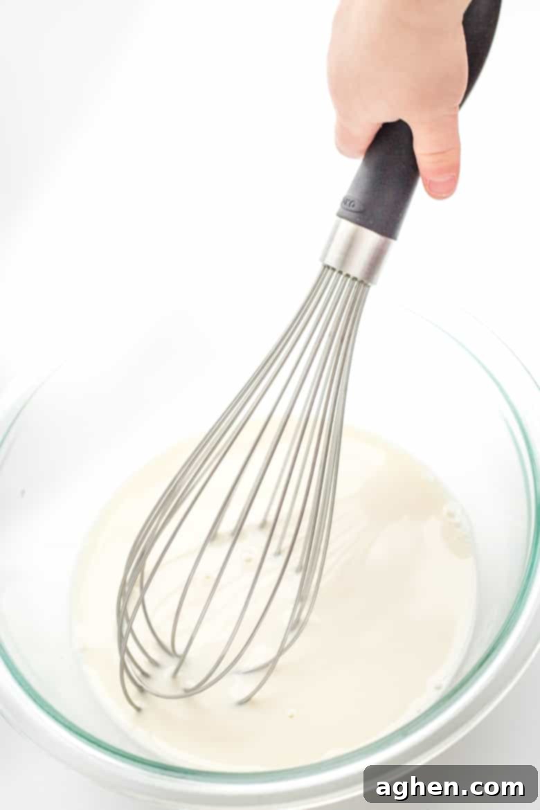 child's hand whisking milk in a bowl