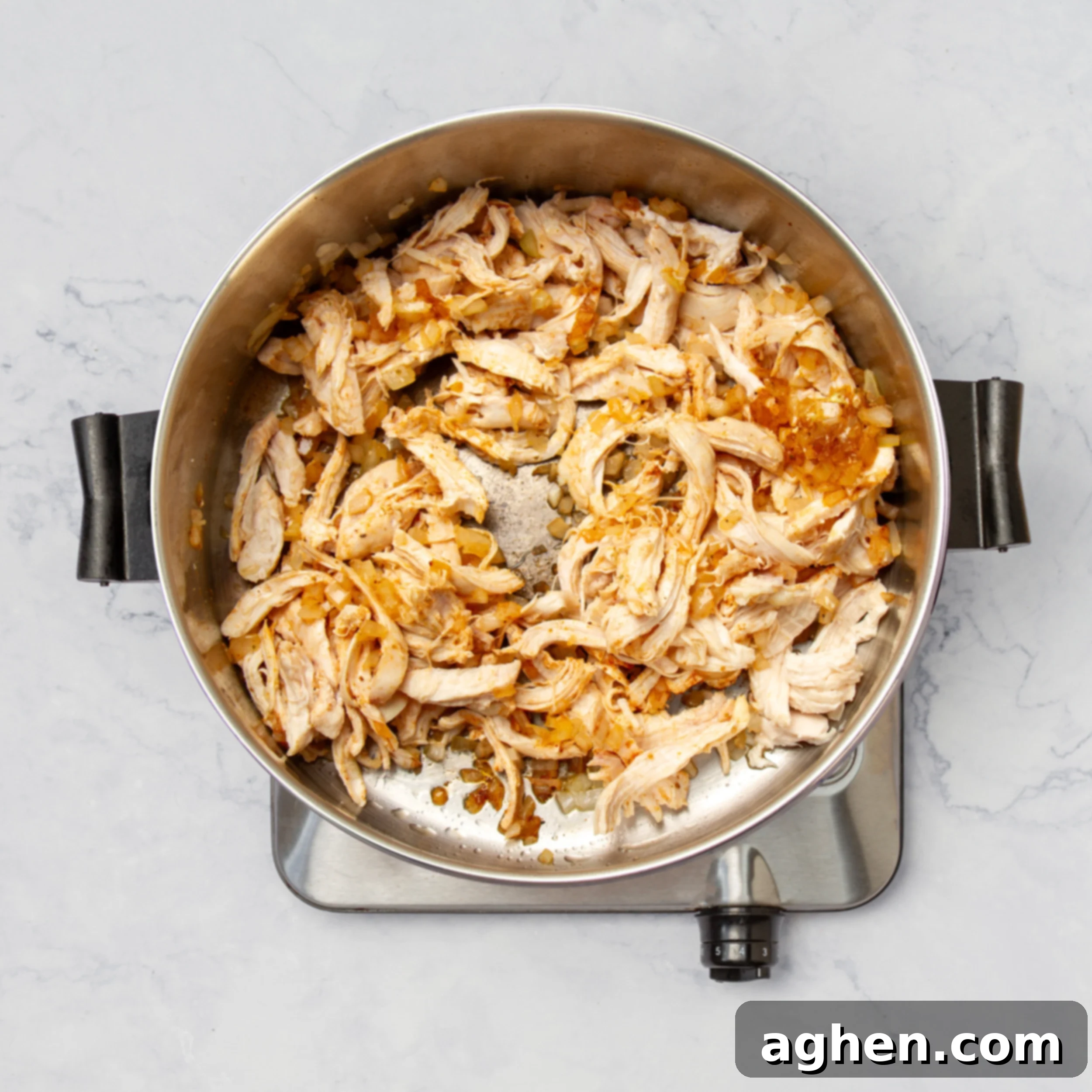 Cheesy Chicken Enchilada Bake 4 Sauted aromatics and shredded chicken heating in a pan.