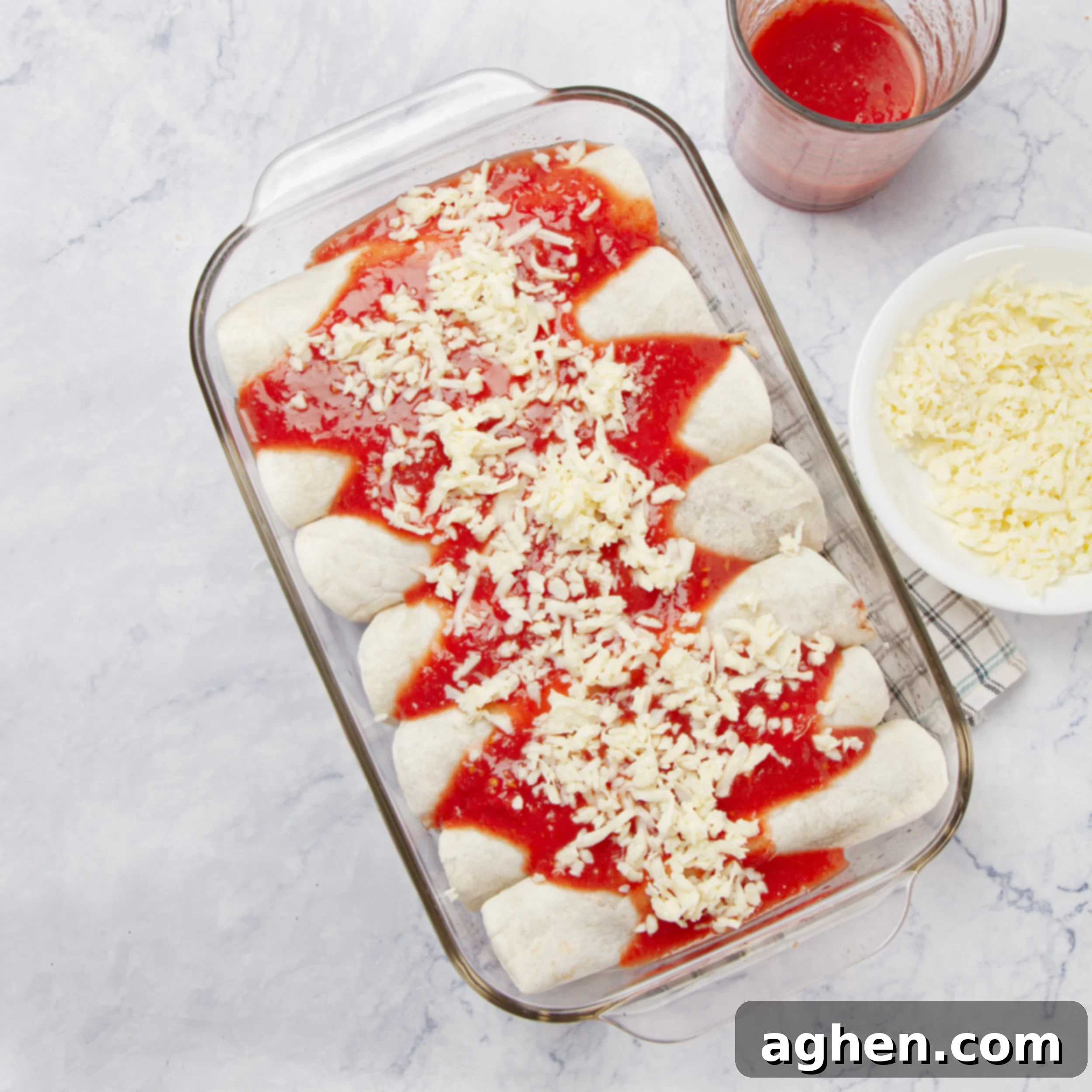 Cheesy Chicken Enchilada Bake 6 Filled and rolled tortillas fit snugly into a glass baking dish, smothered with sauce and shredded cheese.