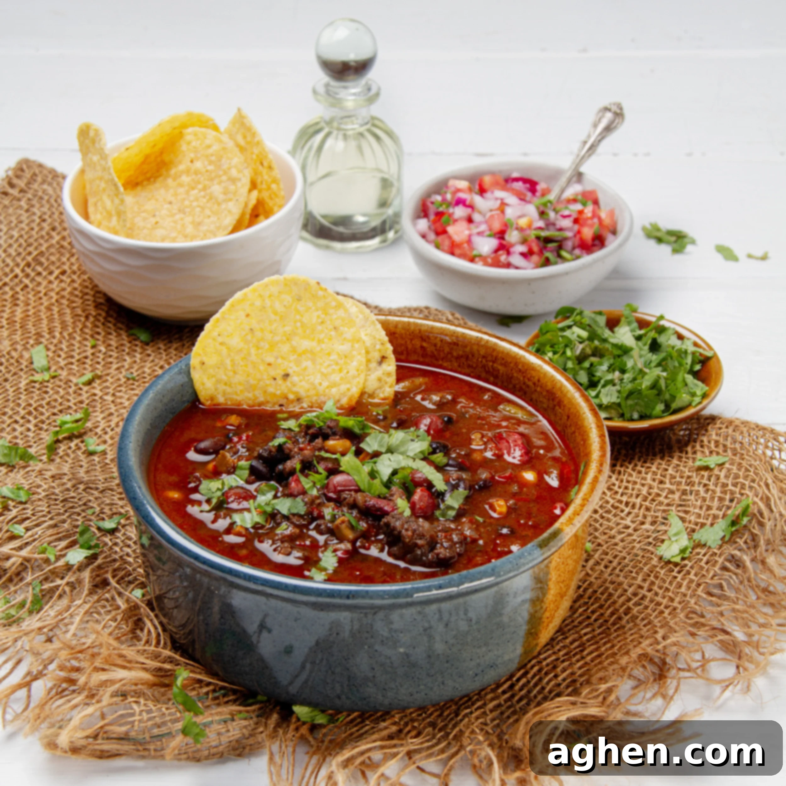 Thick and hearty Cowboy Soup in a bowl with a tortilla chip garnish and cilantro on the side.