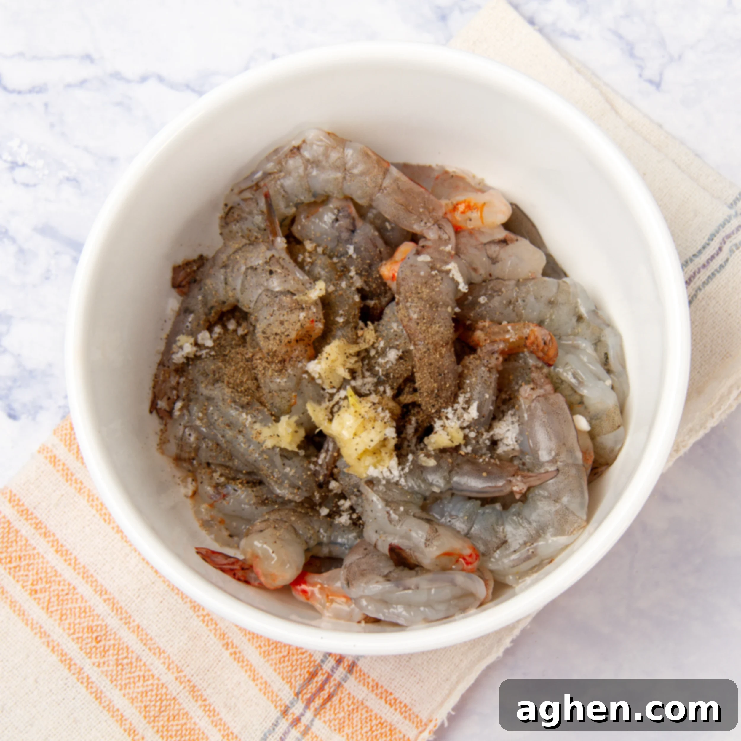 Perfectly Crispy Air Fryer Shrimp 4 Shrimp in a bowl with seasoning.
