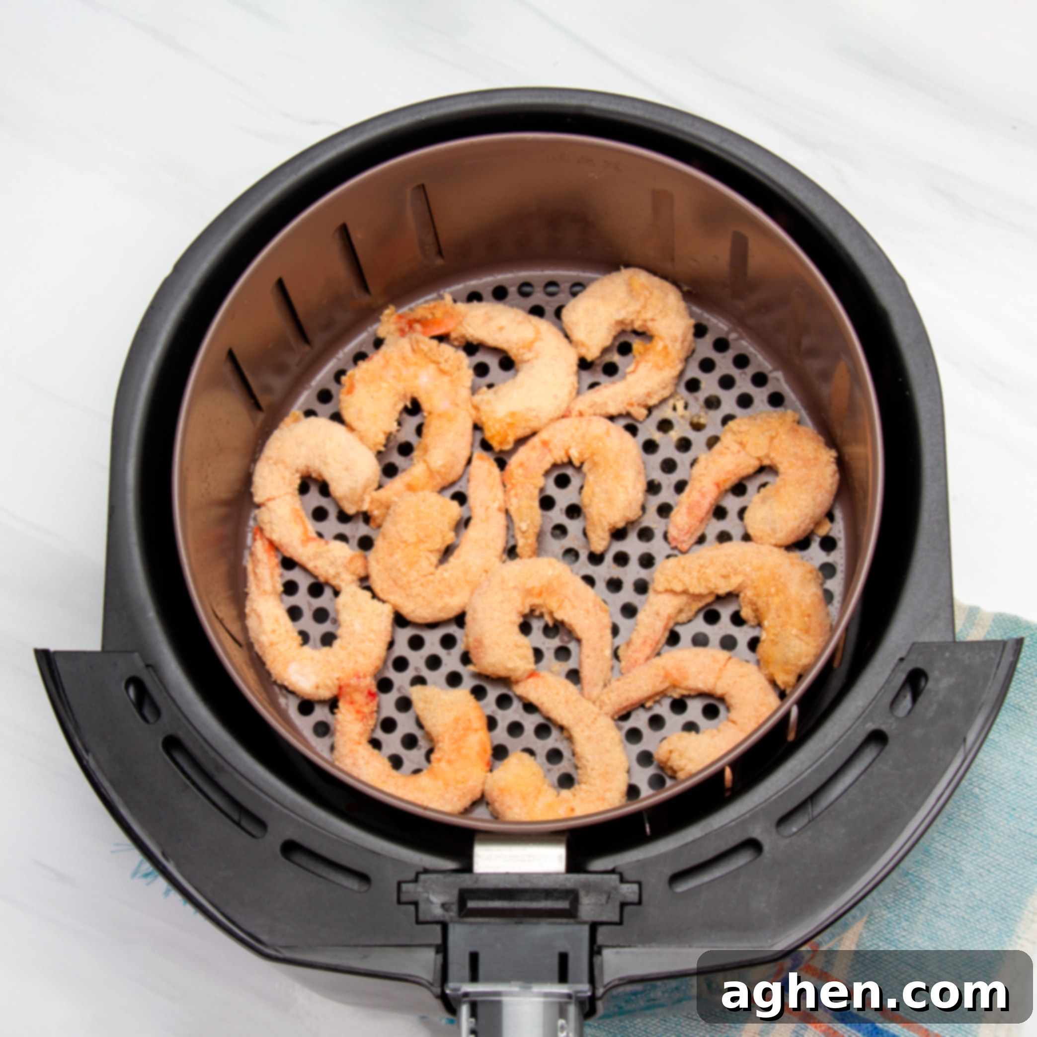 Perfectly Crispy Air Fryer Shrimp 6 Battered shrimp in an sir fryer basket.