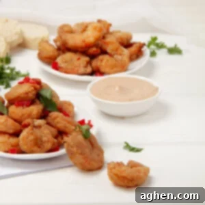 Perfectly Crispy Air Fryer Shrimp 7 Crispy battered Air Fryer Shrimp on a plate with a dish of dipping sauce.