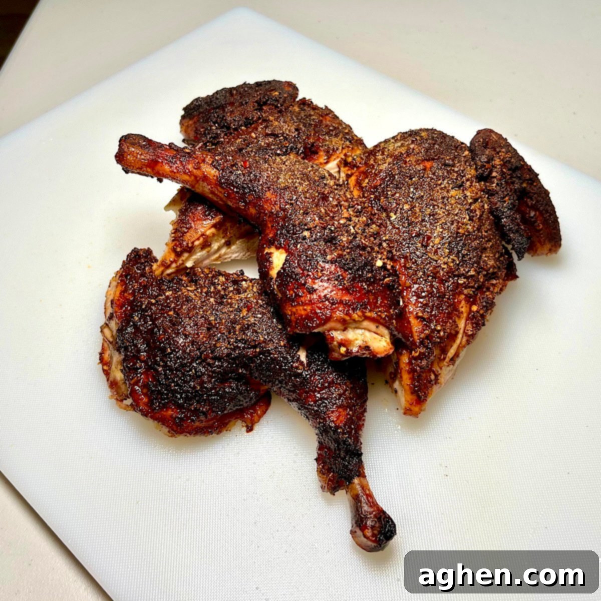 A perfectly grilled spatchcock chicken, expertly cut into quarters, showcasing golden-crispy skin and succulent meat, ready to be served from a rustic wooden board.