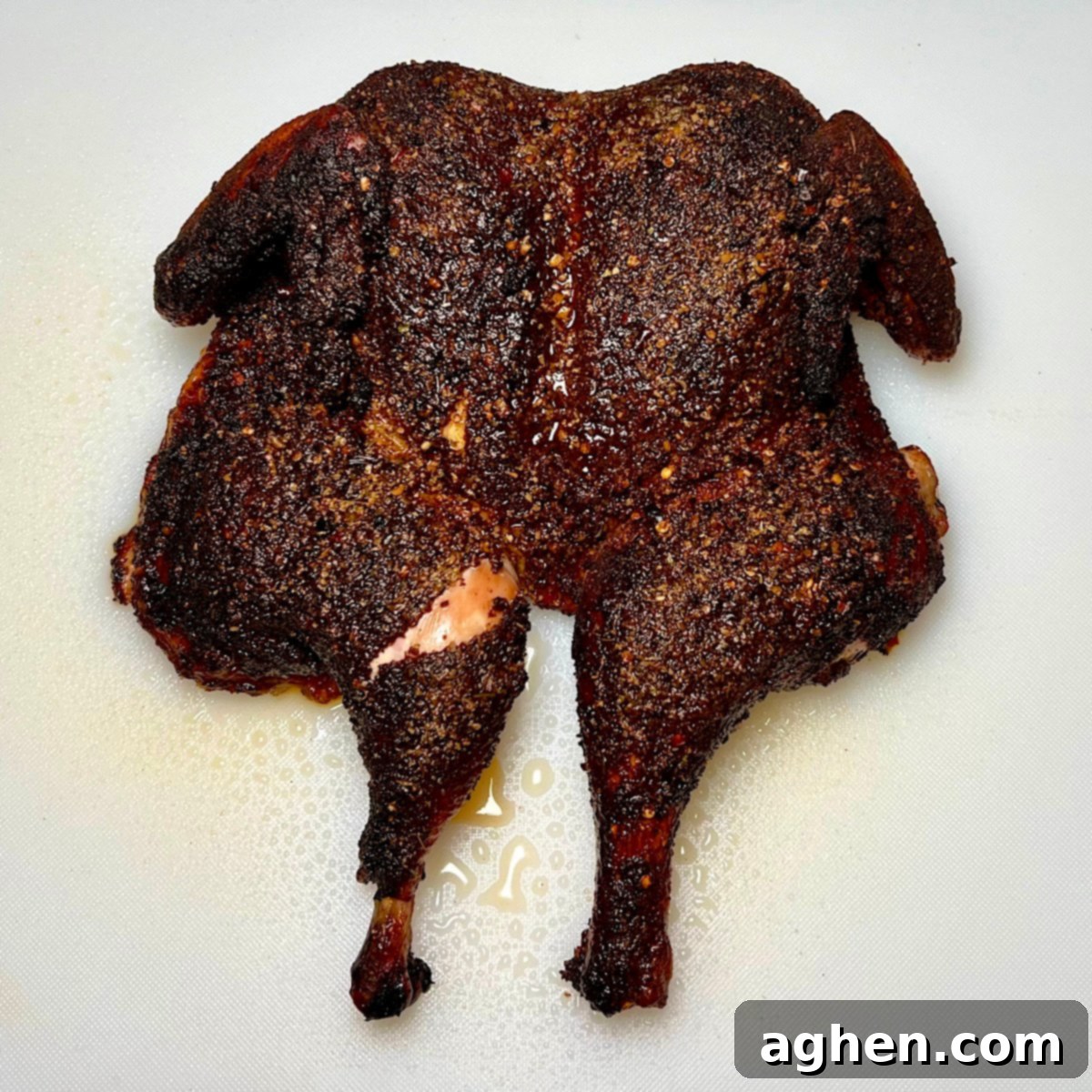 A perfectly grilled and rested spatchcock chicken, golden brown and ready for carving, resting on a wooden board.