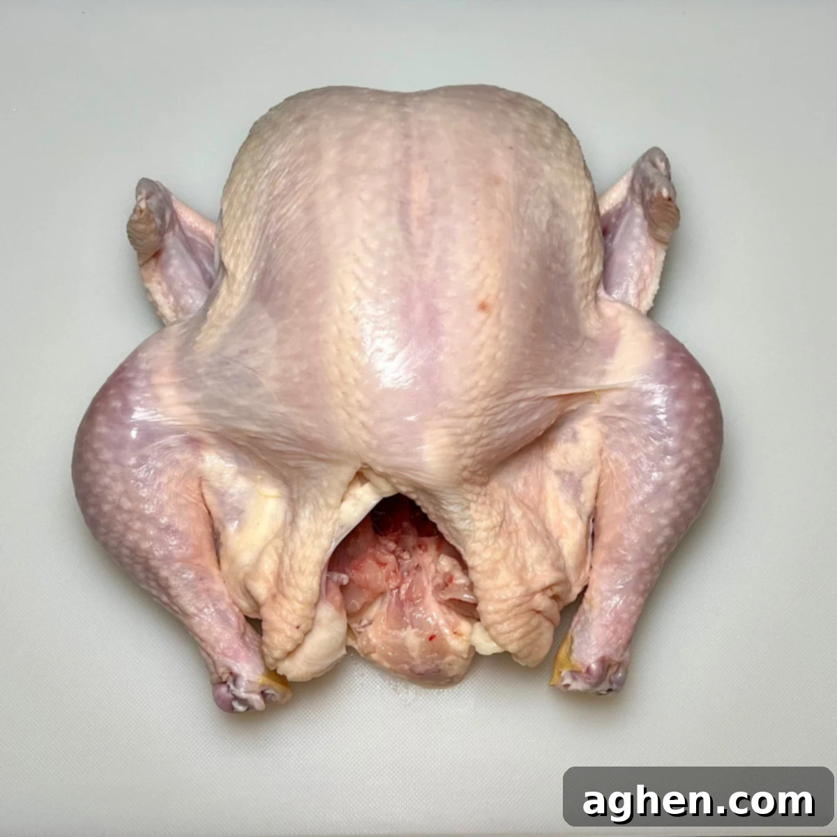 Whole chicken, breast side up, showcasing its natural shape before spatchcocking.