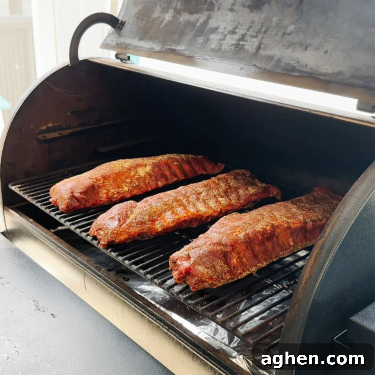 Backyard Rib Wars: Kroger, Smithfield, and Prairie Fresh Face Off 3 Three slabs of baby back ribs smoking on a Traeger grill, showing the consistent cooking environment.
