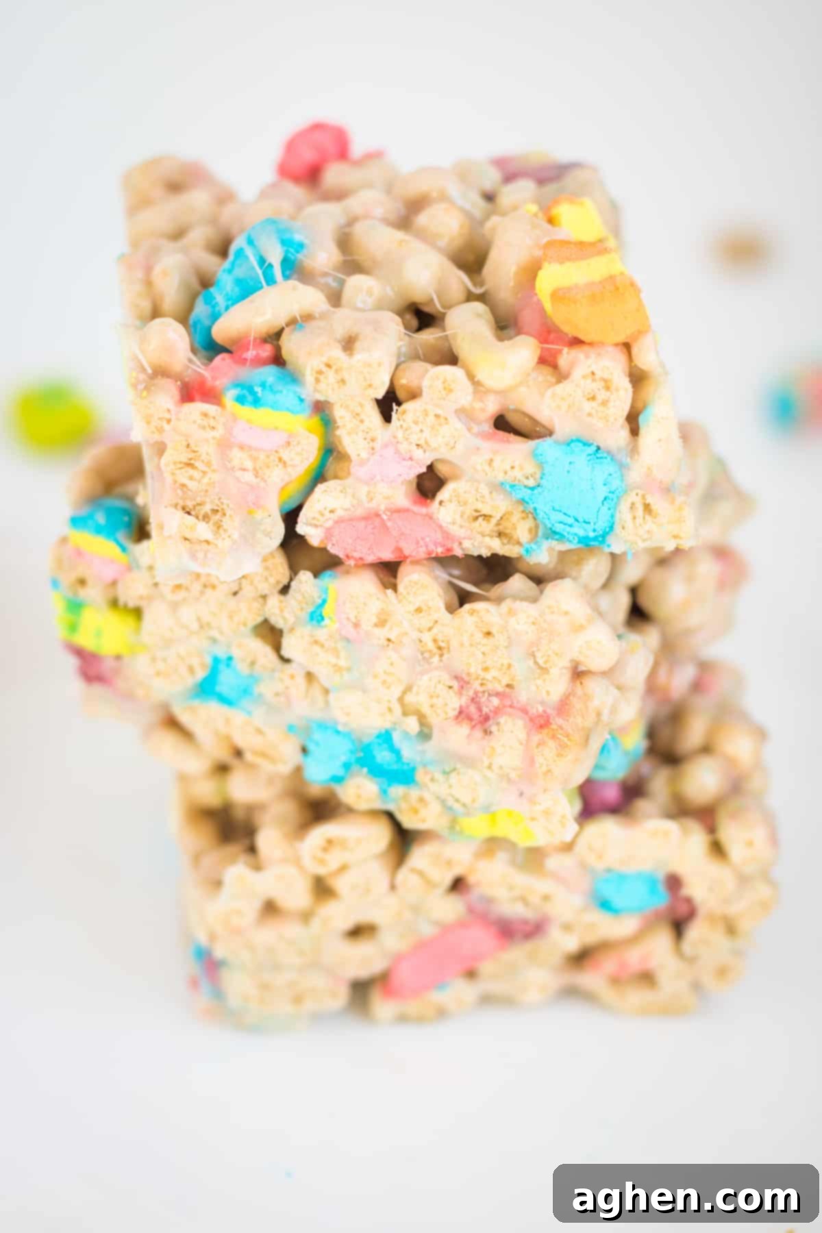 Three lucky charms marshmallow cereal bars cut into squares and stacked on top of one another on a white plate