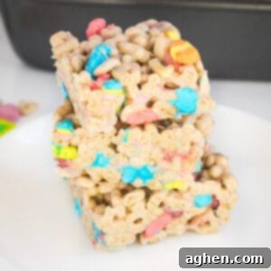 Three lucky charms marshmallow cereal bars cut into squares and stacked on top of one another on a white plate