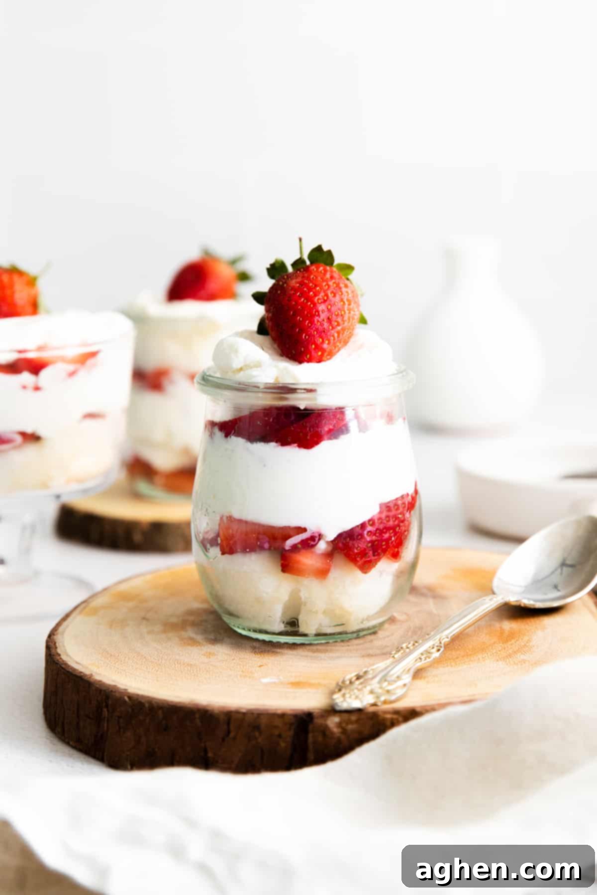 mini strawberry shortcake trifles in glass jars, showing their layers of angel food cake, fresh strawberries, and whipped cream