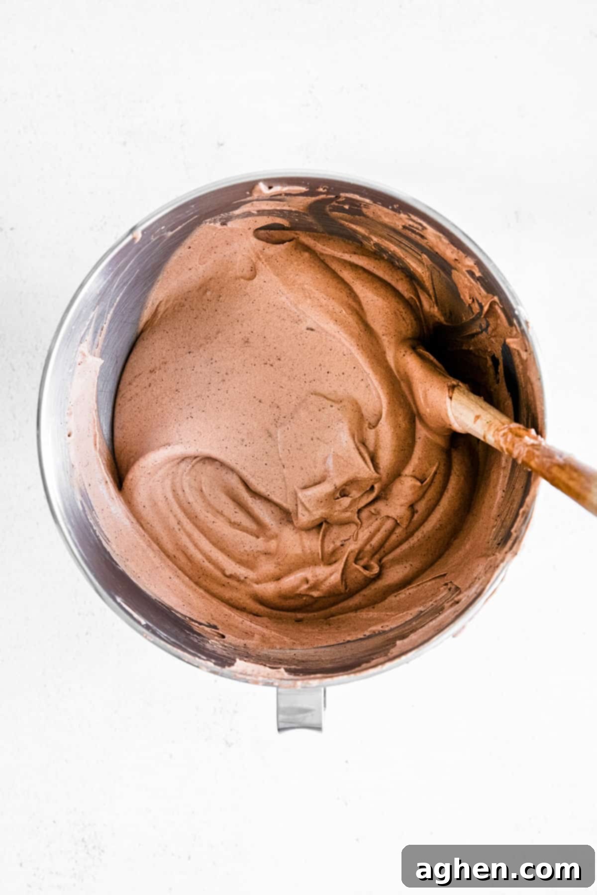 chocolate ice cream mixture in metal bowl with wooden spool