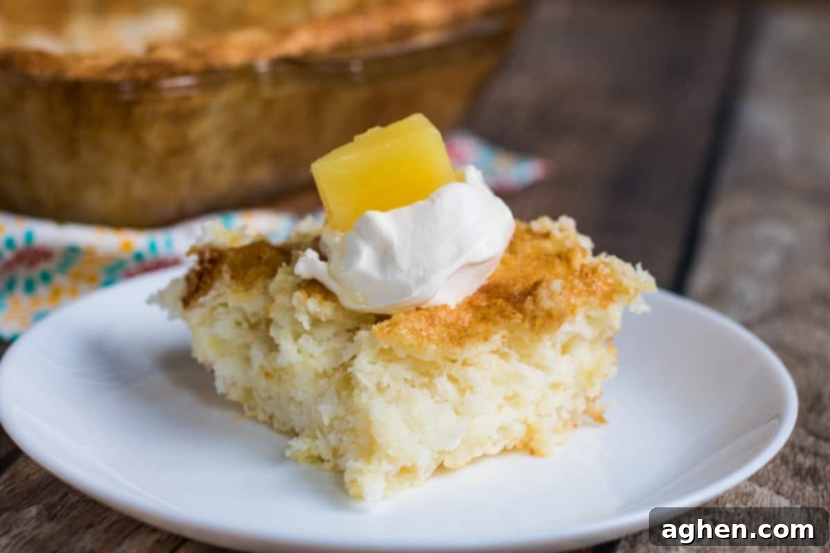 A square slice of fluffy pineapple angel food cake, elegantly topped with whipped cream and a small piece of pineapple.