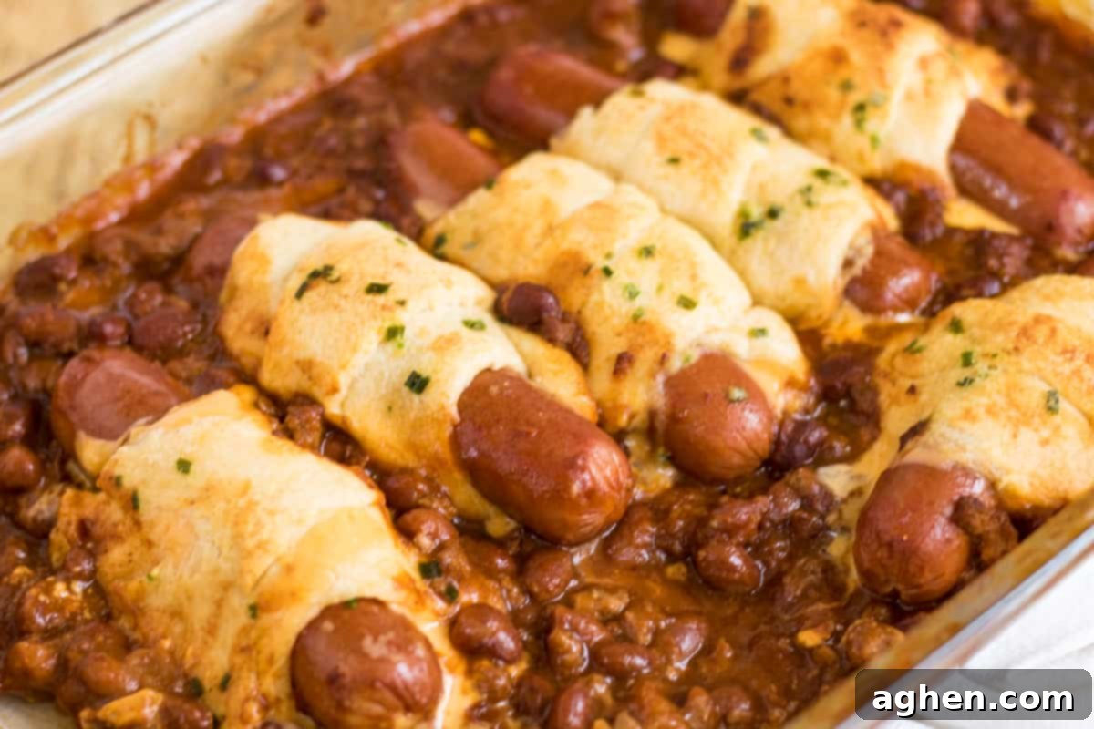 Chili cheese dog casserole made with hot dogs wrapped in cheese and crescent rolls and surrounded by chili