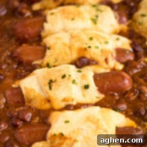 Chili cheese dog casserole made with hot dogs wrapped in cheese and crescent rolls and surrounded by chili