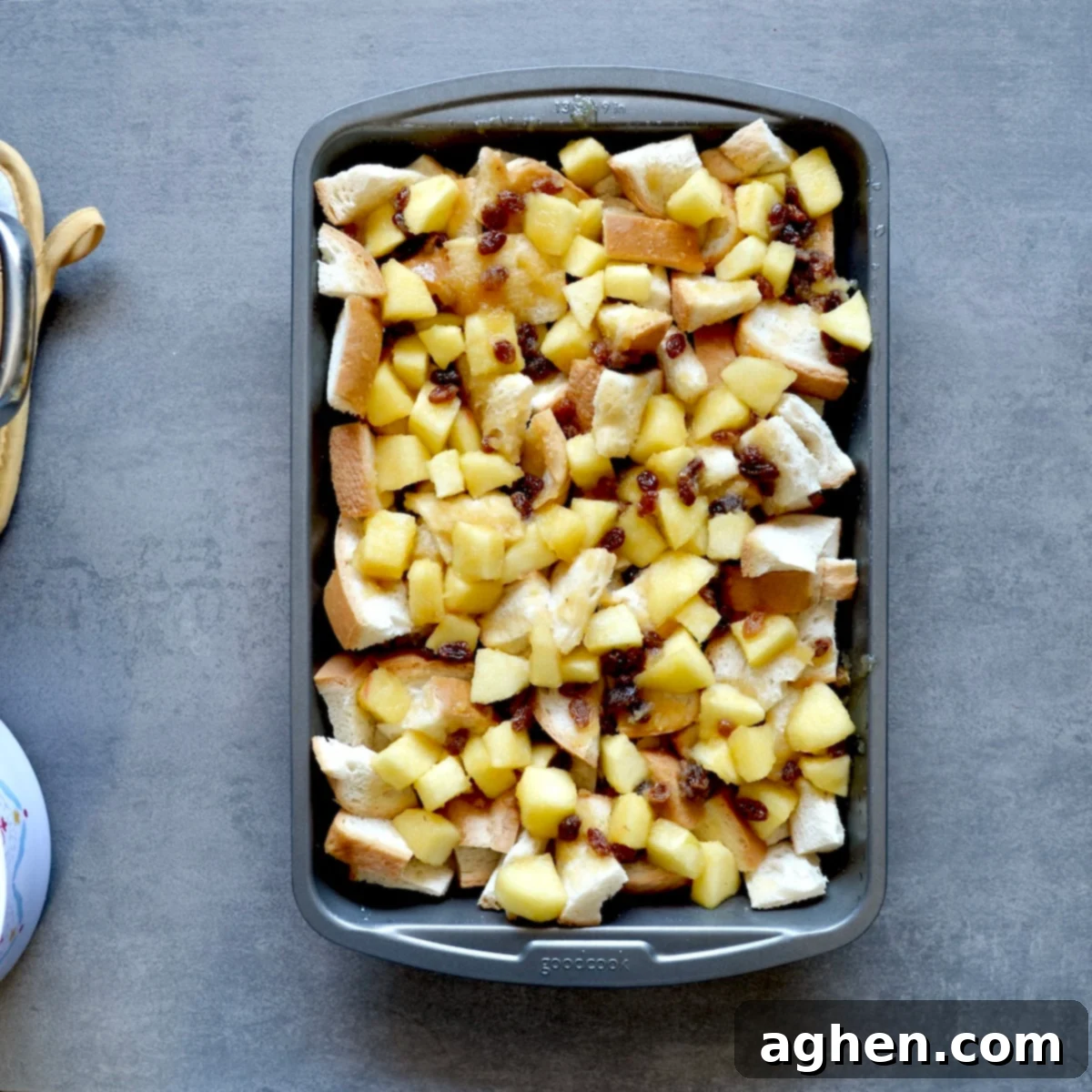 Bread cubes layered with cooked apples and raisins in a baking dish