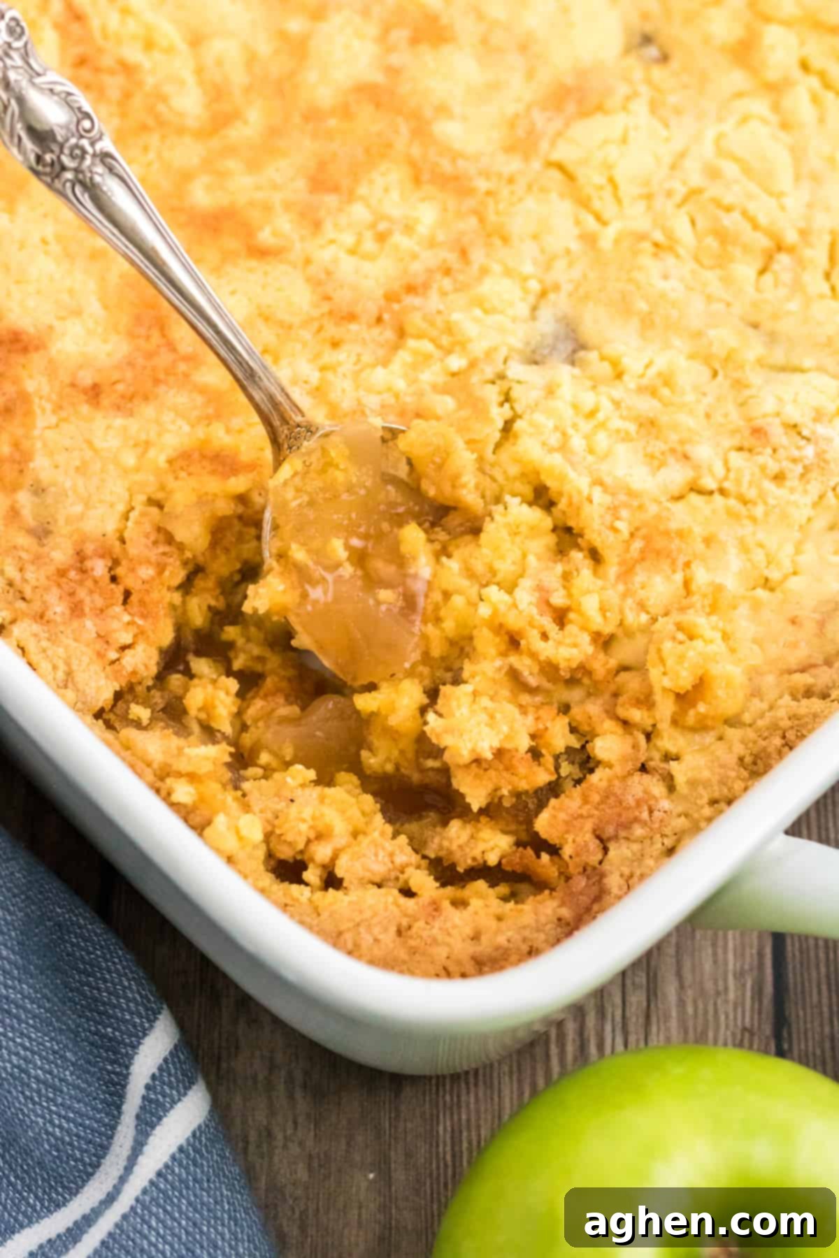 Spoon scopping out apple dump cake from casserole dish.