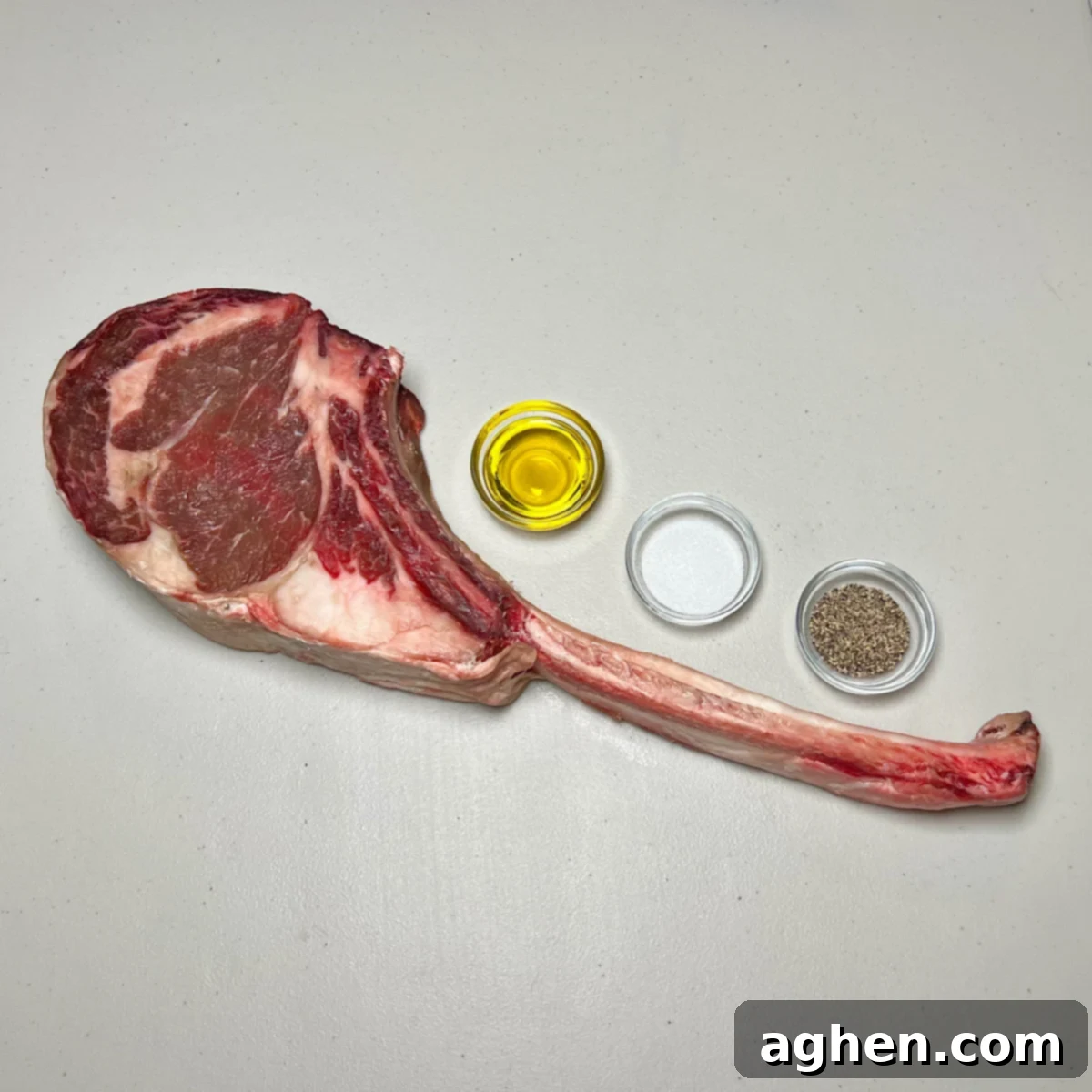 Close-up of a seasoned tomahawk steak with olive oil, salt, and pepper, showcasing the simple ingredients.