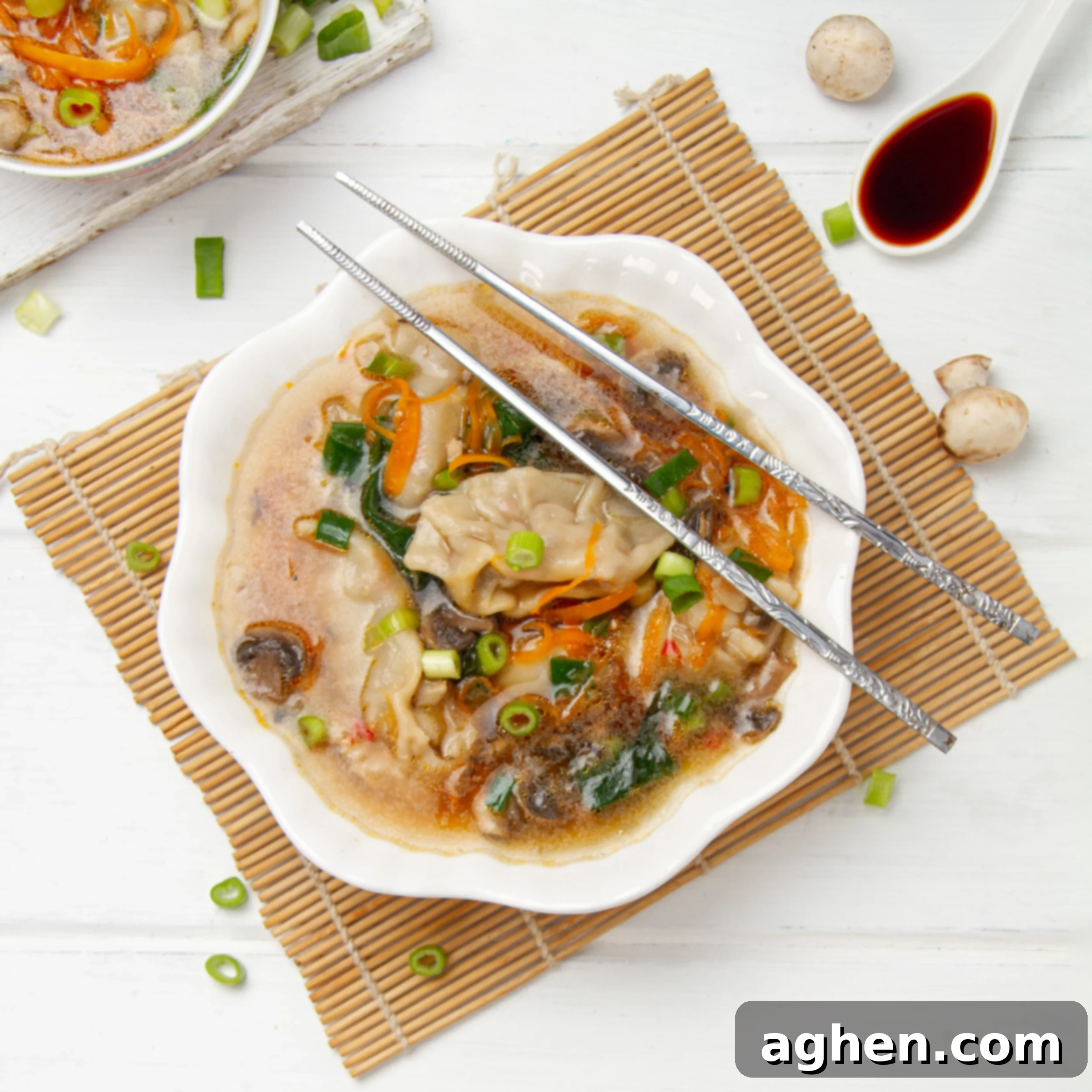 Light yet hearty Chinese dumpling soup in a bowl with chopsticks, garnished with fresh green onions.