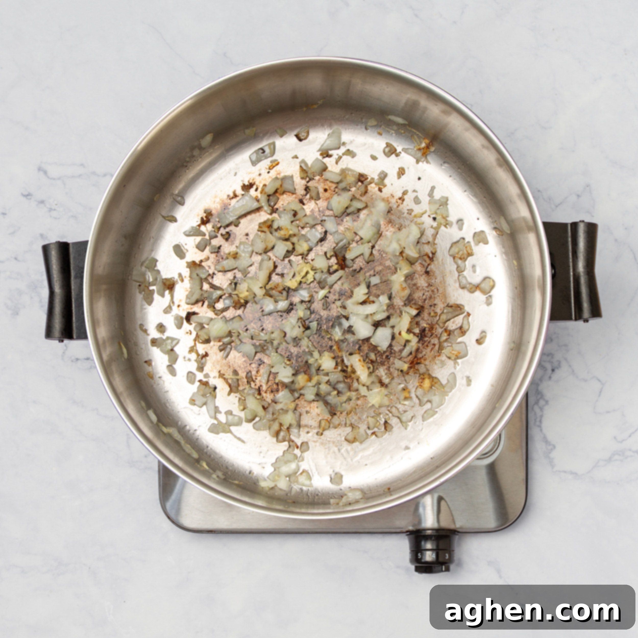 Diced onion, minced garlic, and grated ginger being sautéed in a hot pot with vegetable oil.