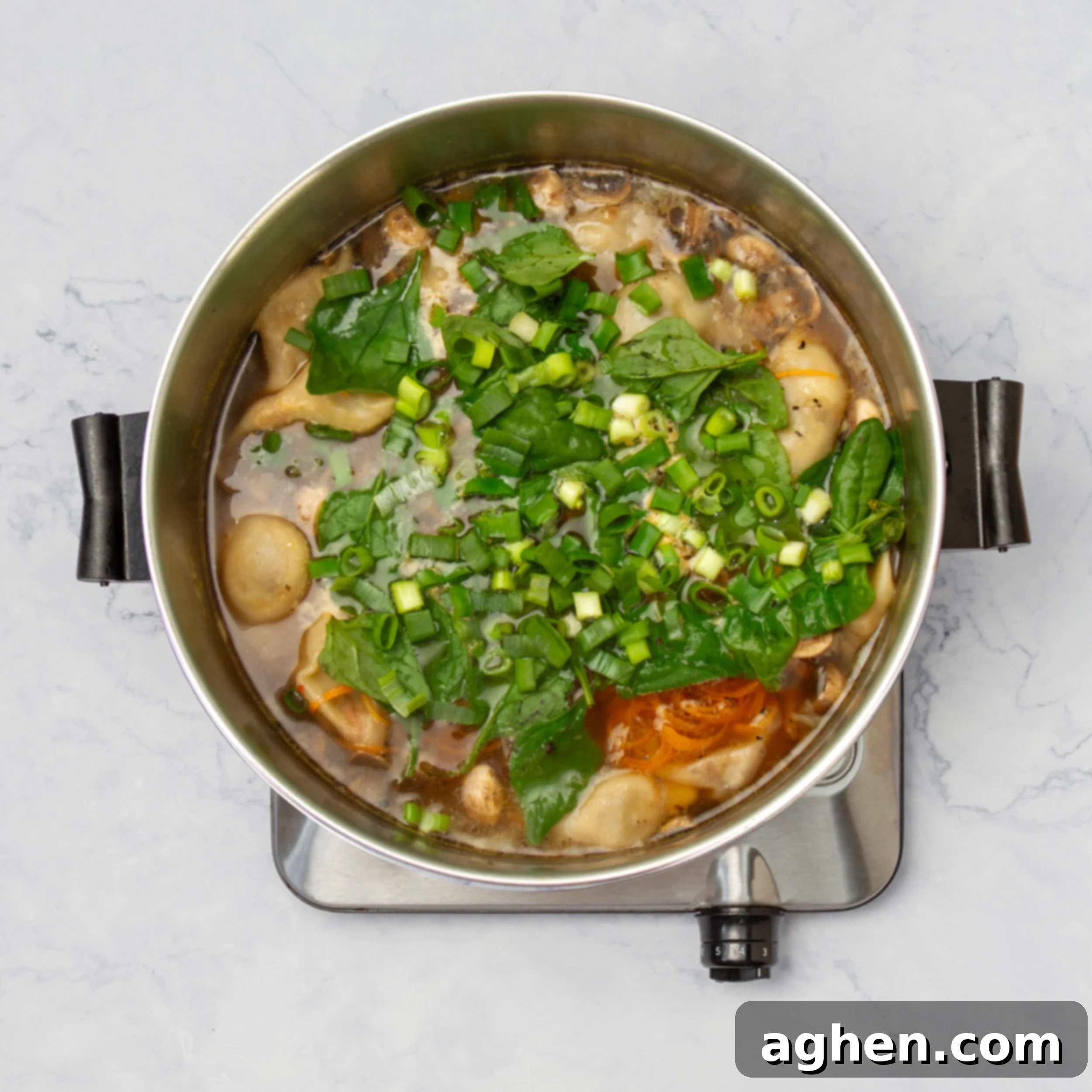 Spiralized carrots, sliced mushrooms, and fresh spinach added to the simmering dumpling soup pot.