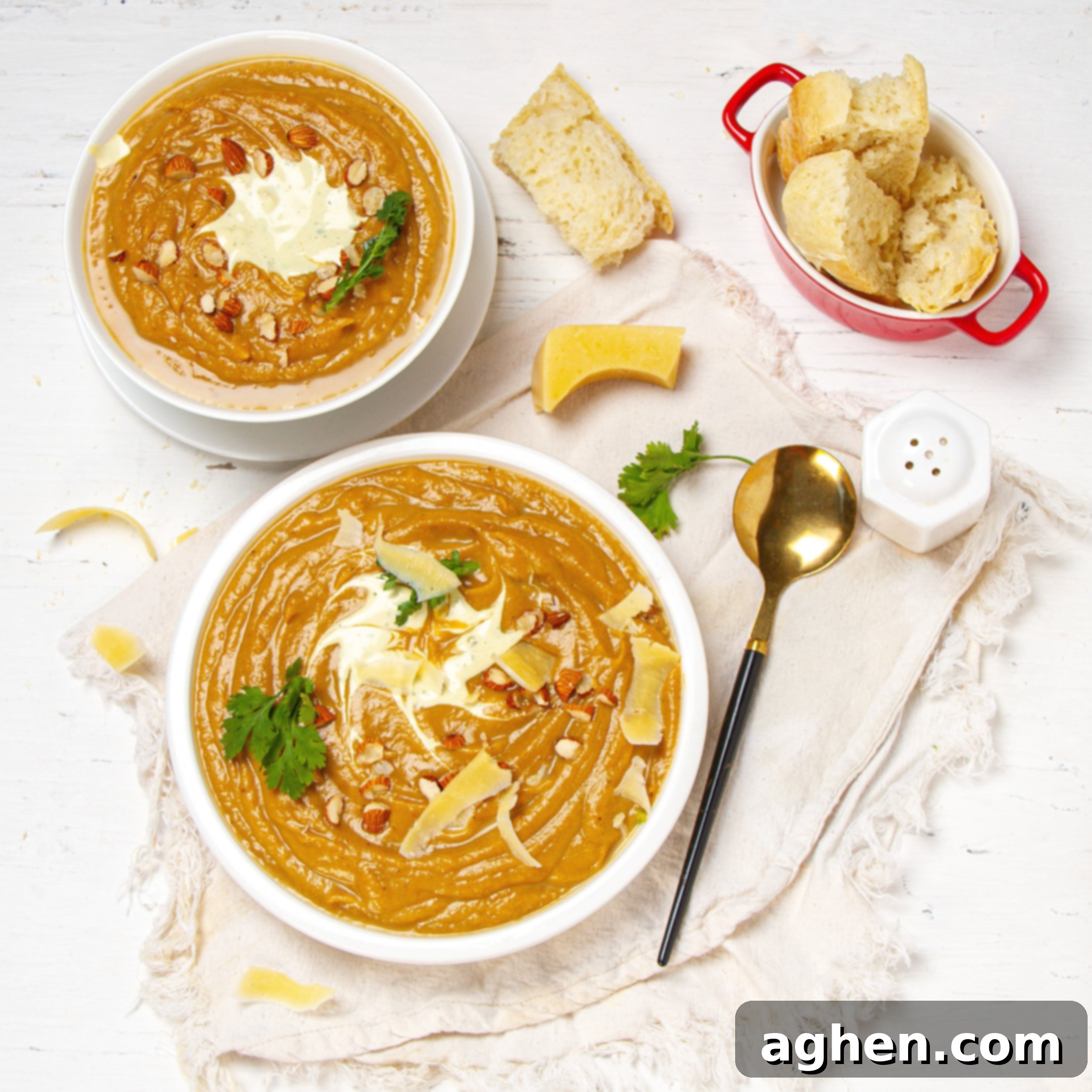 Beautiful and creamy Sweet Potato Soup in two bowls with bread on the side.