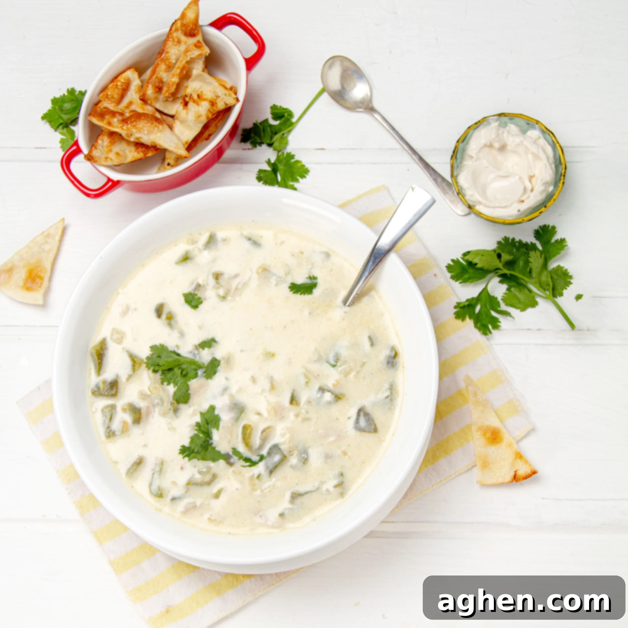 Thicke and creamy Chile Relleno Soup in a bowl with a spoon and bread triangles on the side.