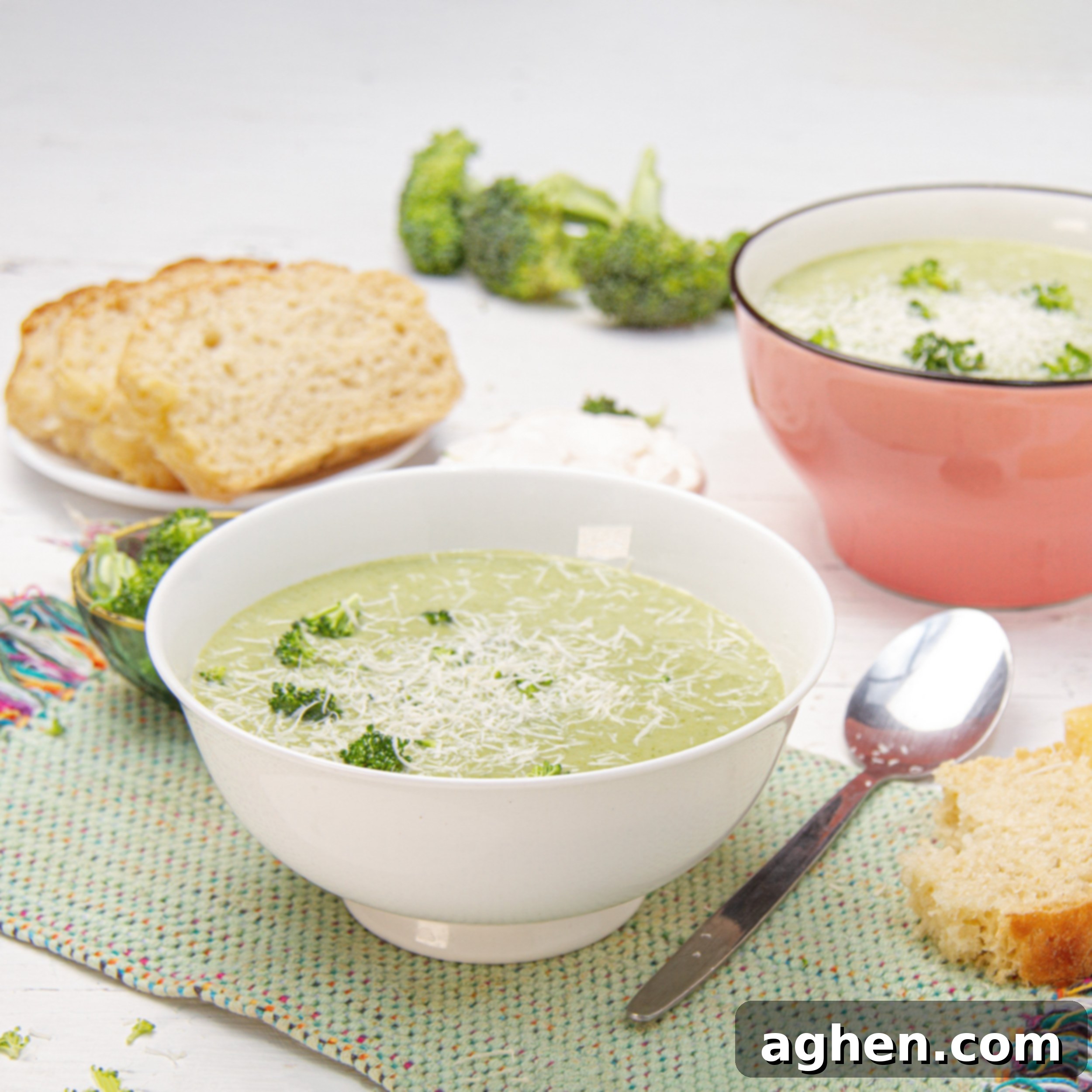 Creamy and delicious Broccoli Cream Soup in a bowl with a spoon and bread on the side.