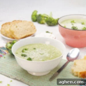 Creamy and delicious Broccoli Cream Soup in a bowl with a spoon and bread on the side.