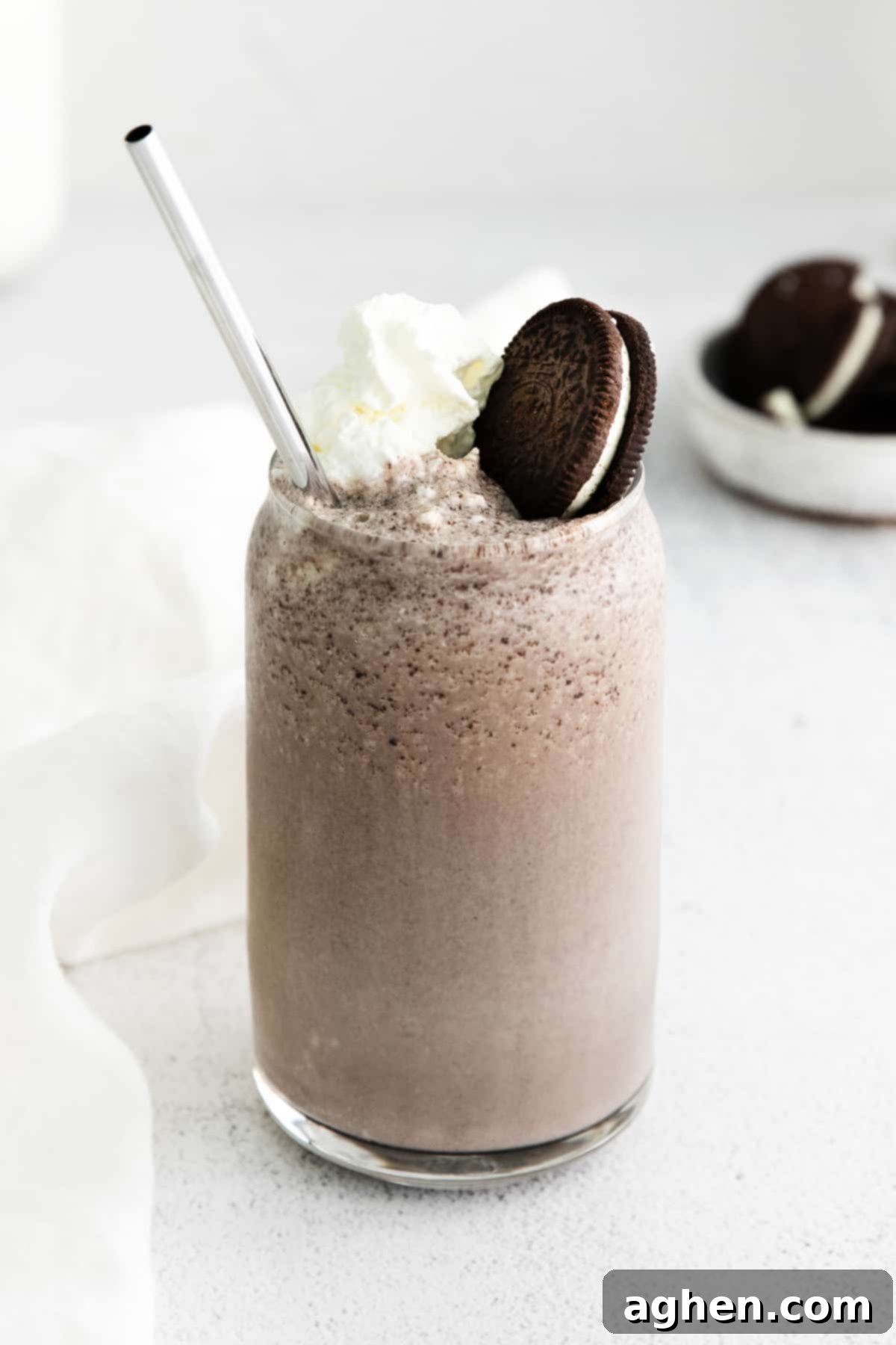 Decadent Boozy Oreo Milkshake served in a tall glass, garnished with a generous swirl of whipped cream and a whole OREO cookie, ready for a luxurious sip.