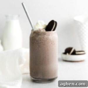A delicious Boozy Oreo Milkshake in a tall glass, garnished with whipped cream, an OREO cookie, and a straw.