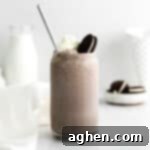 Close-up of a Boozy Oreo Milkshake in a glass, with whipped cream and an OREO on top.