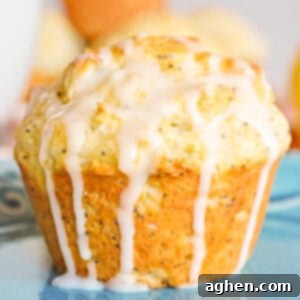 A freshly baked lemon poppy seed muffin, generously drizzled with a sweet lemon glaze cascading down its sides, inviting you to take a bite.
