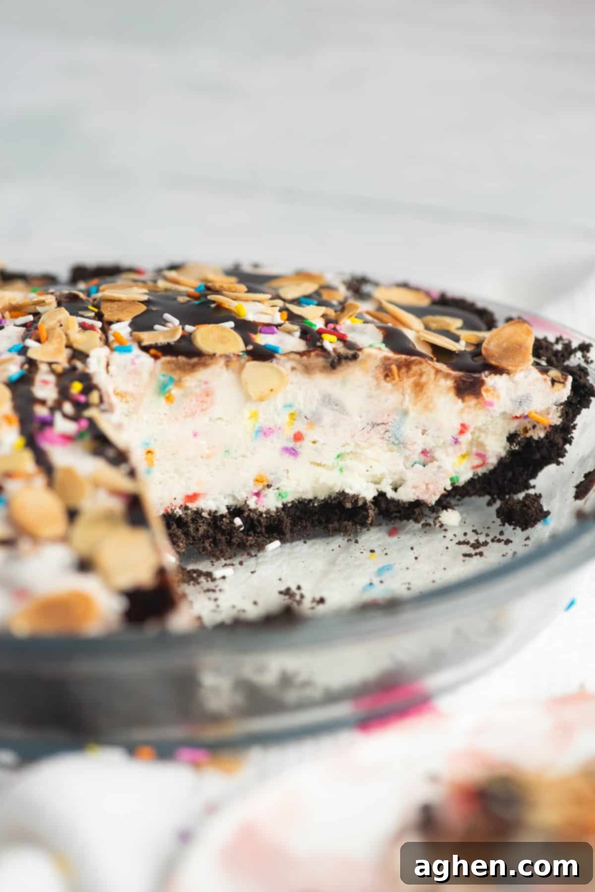 Frozen Dream Pie 3 Ice cream cake in a glass pie plate. Vanilla ice cream pie is in chocolate cookie crust and topped with sprinkles and chocolate sauce