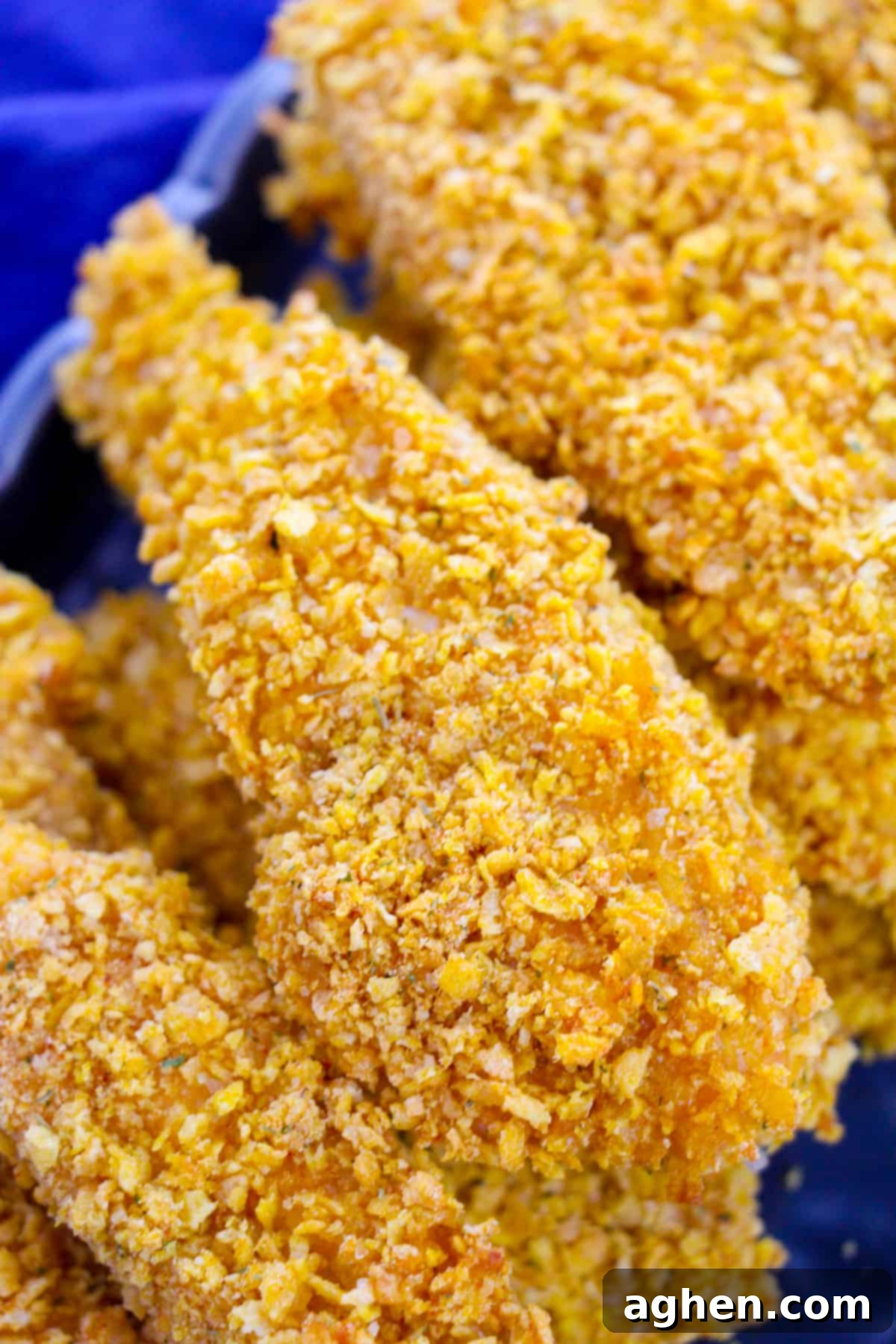 Close-up image of a single chicken tender showcasing its perfectly golden and crunchy cornflake coating, ready for dipping.