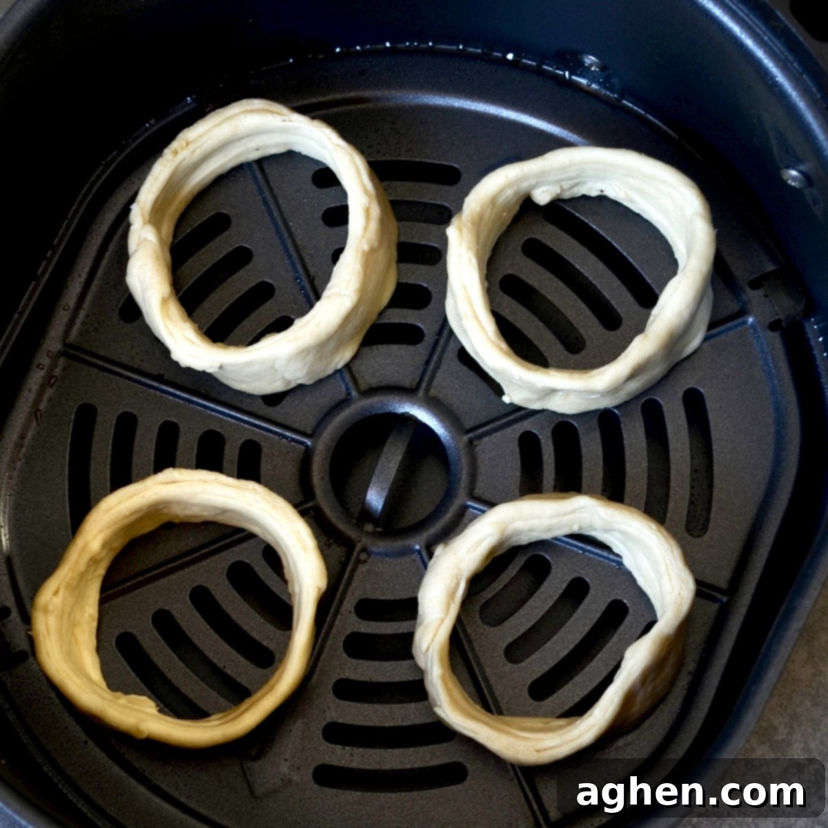 Unbaked, shaped crescent cronuts placed in a single layer in an air fryer basket, lightly sprayed with cooking spray.