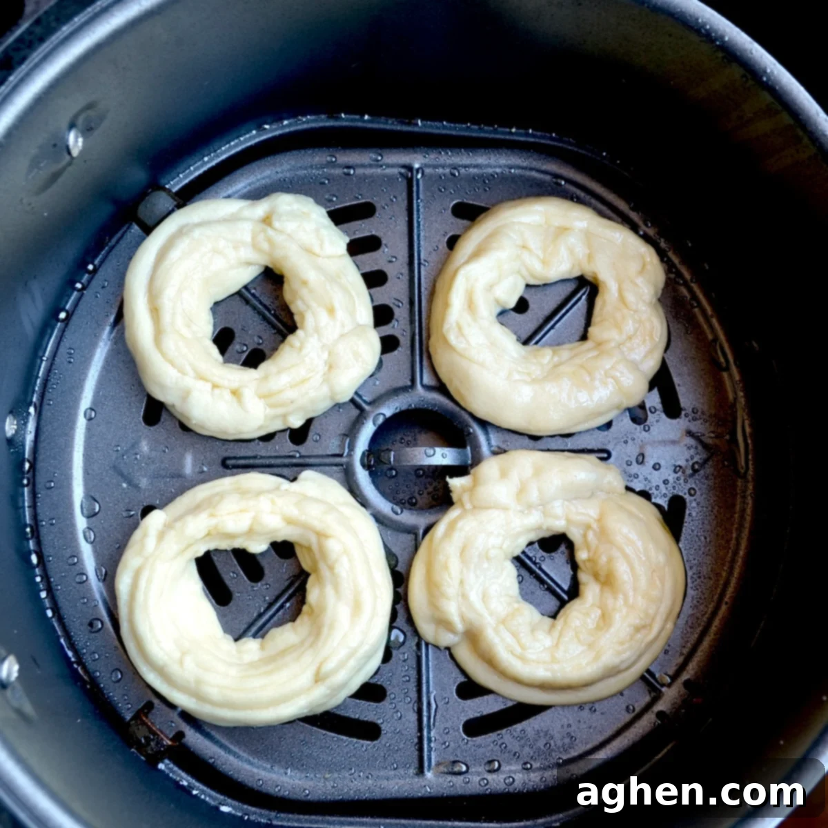 Puffed up crescent cronut dough in an air fryer basket after the initial low-temperature cooking phase.